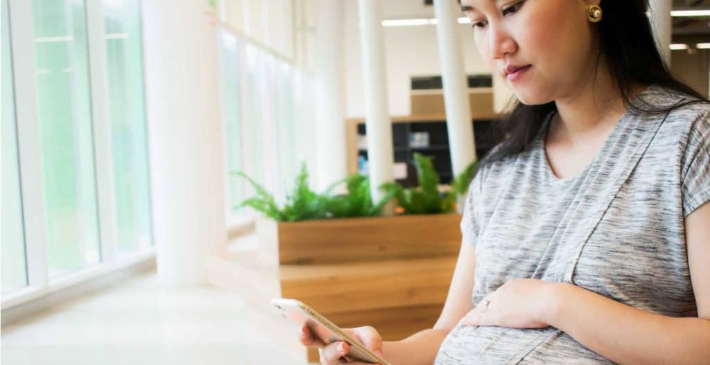 Pregnant person looks at smartphone