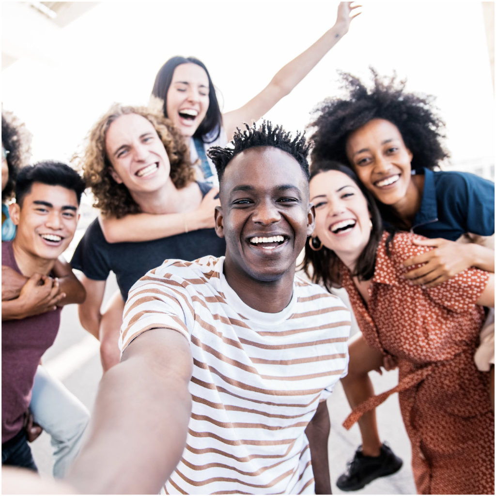 Image of a group of ethnically diverse friends laughing, smiling, and hugging